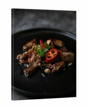 Closeup shot of Korean Galbi Jjim, braised short ribs with spring onion and pepper in black plate