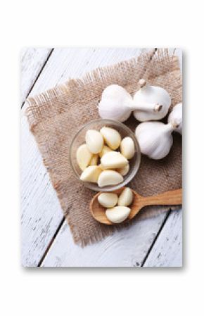 Fresh sliced garlic in glass bowl on wooden background