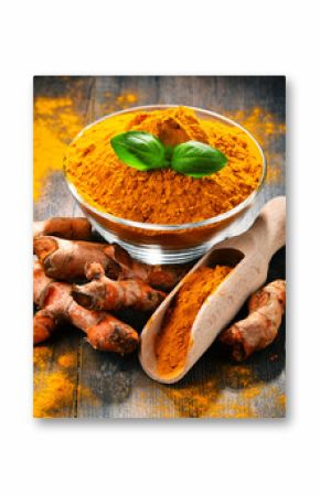 Composition with bowl of turmeric powder on wooden table