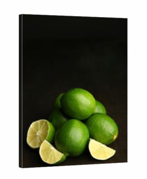 Fresh juicy limes on wooden table, on dark background