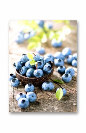 Organic blueberries with green leaves over rustic wooden table