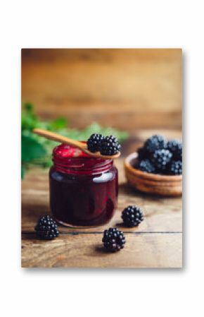 Fresh homemade blackberry jam in glass jar on a wooden background  