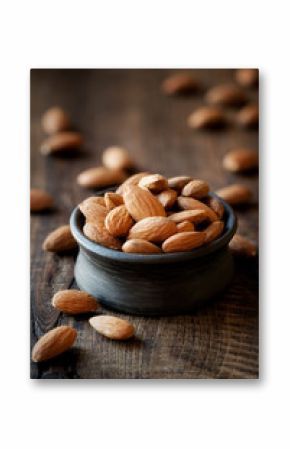 Almonds in a black bowl against dark rustic wooden background