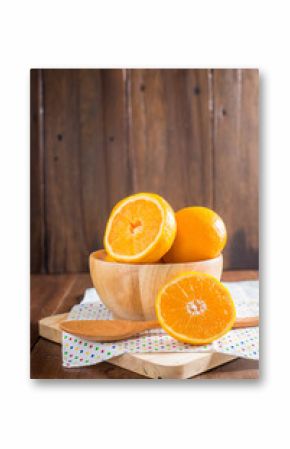 oranges in a wooden bowl on wooden background.