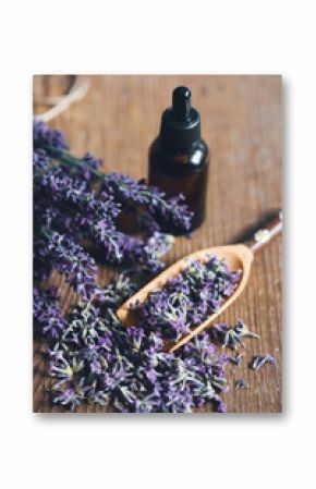 Bottle with aroma oil and lavender flowers on blue background