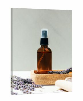 Set of natural cosmetics. Amber bottles with facial, bath liquid on a concrete background with lavender flowers. Front view