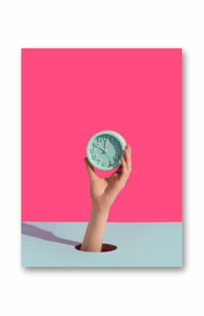Female hands holding alarm clock through hole on color background