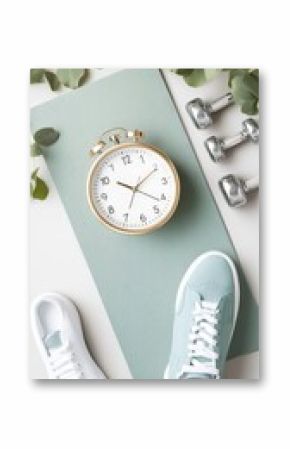 Pastel pink and green yoga mat paired with dumbbells and a light blue sneaker, elegantly arranged on a clean gray surface, perfect for a fitness lifestyle