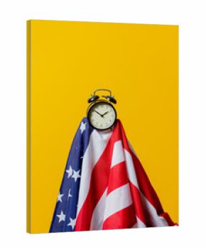 USA flag and alarm clock on yellow background