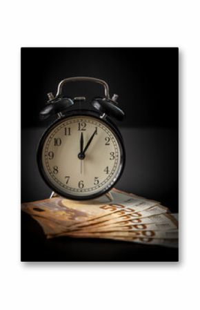 Alarm clock and money on black background. Time is money concept