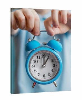 The blue alarm clock is held by children's hands.