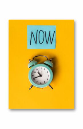Alarm clock and a colored sticker with the inscription NOW on a yellow background
