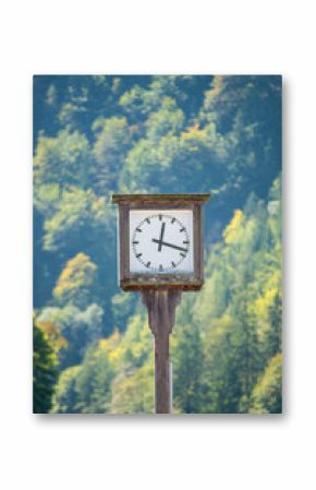 Close up view of a clock  with the forest and a mountain  in the backgroud