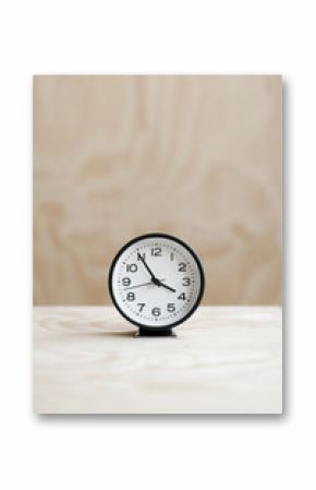 analog alarm clock on wood table with plywood backdrop