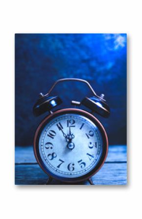 Old, vintage, retro alarm clock on wooden table at night in moonlight.