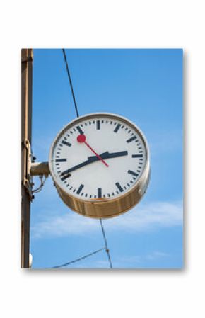 Generic analog clock outside train station platform in Europe. Close, looking up shot, blue sky background, no people