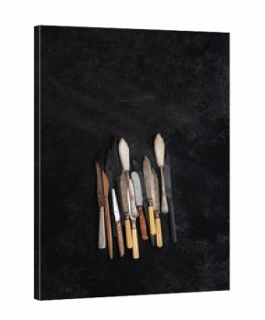 From above of collection of vintage knives placed on black background in studio