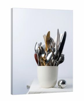 Set of cutlery of spoons, knives and forks in cup with holiday decorations on dining table, copy space