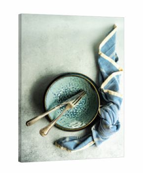 Overhead view of a blue ceramic bowl with cutlery and a napkin