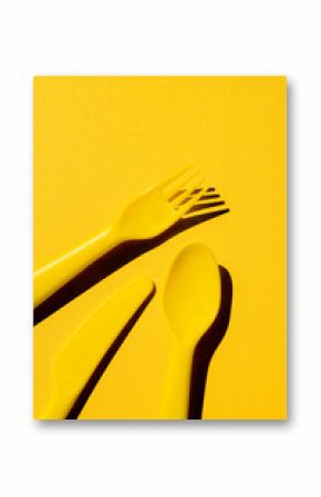 Yellow plastic utensils with a hard shadow