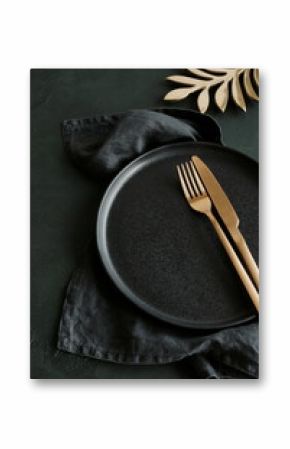 Empty black ceramic plate and cutlery on black background top view with copy space . Modern kitchen utensils.Space for text or menu .Business food brand template.