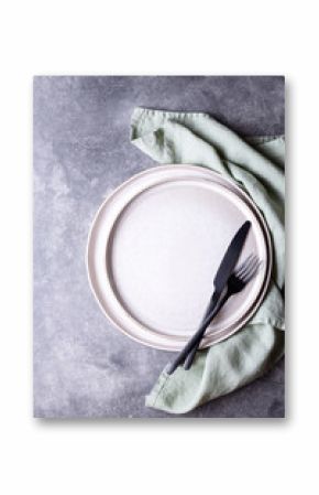 Plates and black cutlery on stone table.