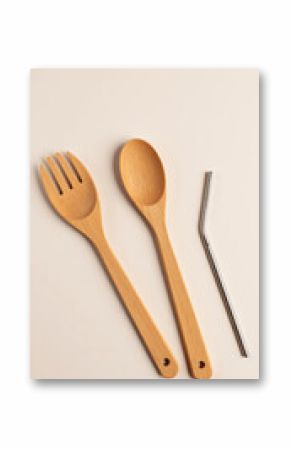 Wooden kitchen utensils including spoon, fork, and straw on beige background  