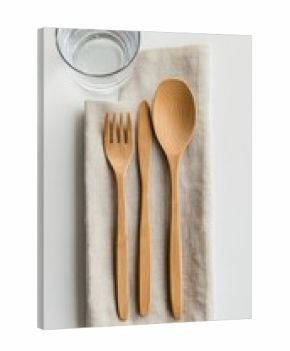 Wooden cutlery set on a linen napkin with a glass of water