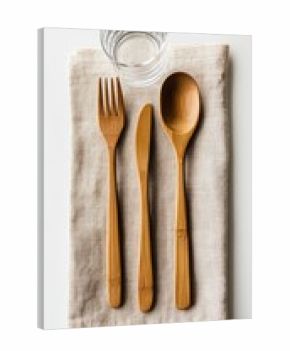 Wooden cutlery set on linen napkin, with water glass