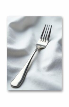 A gleaming silver fork rests on crisp white linen , elegant, minimalist