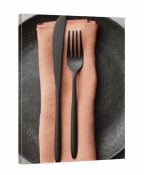 Flatlay of matte black cutlery on a peach linen napkin, atop a dark gray plate