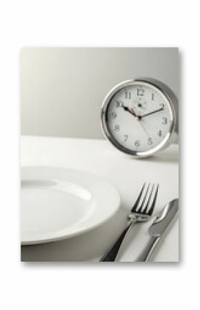 Empty plate and cutlery with a clock in the background.