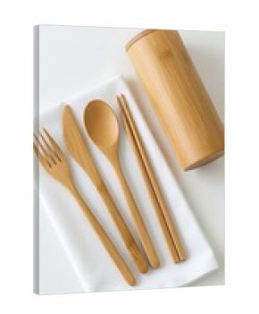 A set of bamboo cutlery including a fork knife spoon chopsticks and case on a white cloth surface