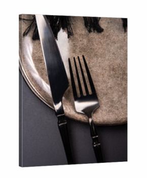 Beautiful table setting, beautiful plate, cutlery and napkin placed on a dark background, selective focus.