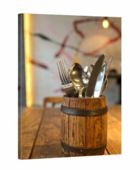 Wooden barrel-shaped utensil holder with cutlery on a rustic table