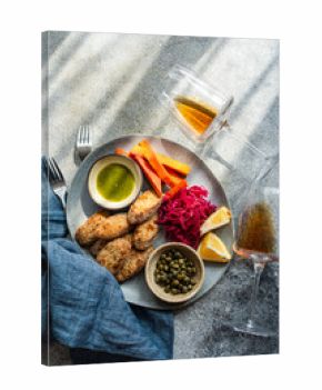 Breaded chicken slices with roasted pumpkin, pickled red cabbage and beetroot (pelustka), capers, traditional sour cherry sauce (tkmemali) and  amber wine on a table