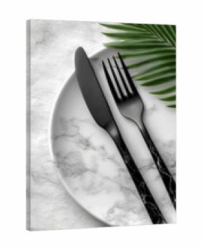 Elegant black cutlery on marble plate, palm leaf