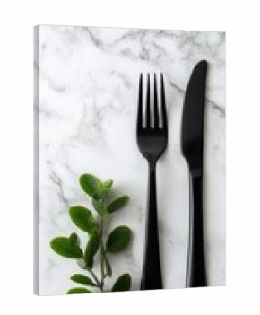 Black cutlery on marble with greenery (1)
