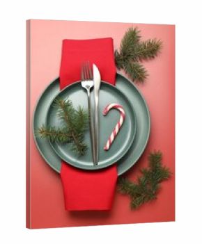 Christmas setting with plates, cutlery and fir tree branches on red background, flat lay