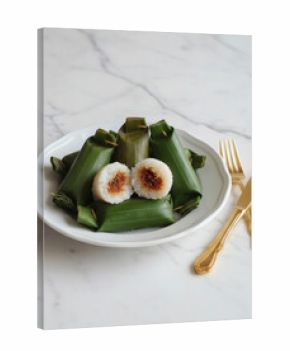 Arem-Arem, an Indonesian savory rice roll with spiced meat and vegetable filling, wrapped in banana leaves and served with elegant gold cutlery
