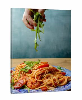 Pasta with shrimps, arugula and tomatoes isolated. Female hands with cutlery