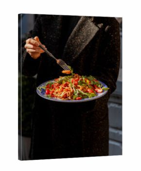 Pasta with shrimps, arugula and tomatoes isolated. Female hands with cutlery