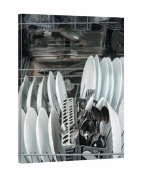 Close-up of loaded dishwasher with clean plates and cutlery