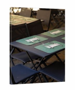 Empty outdoor restaurant tables with placemats and cutlery set