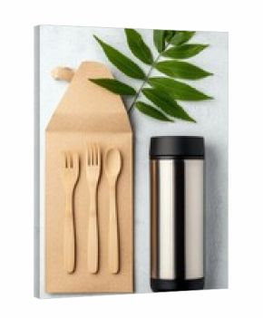 A set of reusable bamboo cutlery in a brown paper holder sits next to a stainless steel thermos, with a green leaf accenting the composition.
