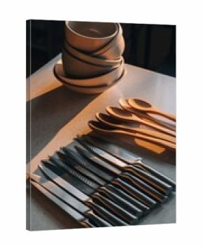 Stacked bowls and cutlery arranged on a surface with dramatic lighting.