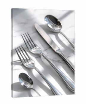Polished stainless steel cutlery set on a white marble surface with soft daylight