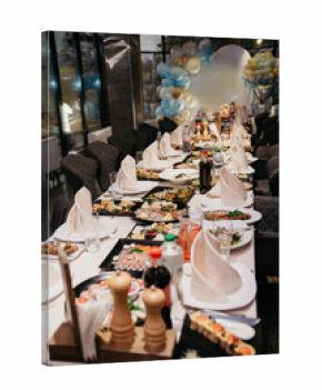 In the restaurant, before the holiday begins, plates, napkins, cutlery and food are placed on tables covered with tablecloths.
