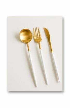 Modern cutlery set gold white colors on light beige background top view with copy space. Elegant table setting.