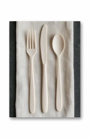 Biodegradable cutlery set made from cornstarch, featuring fork, knife, and spoon, arranged on linen napkin, ideal for eco friendly dining experiences